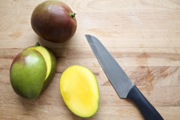 mangos, sliced in half, knife